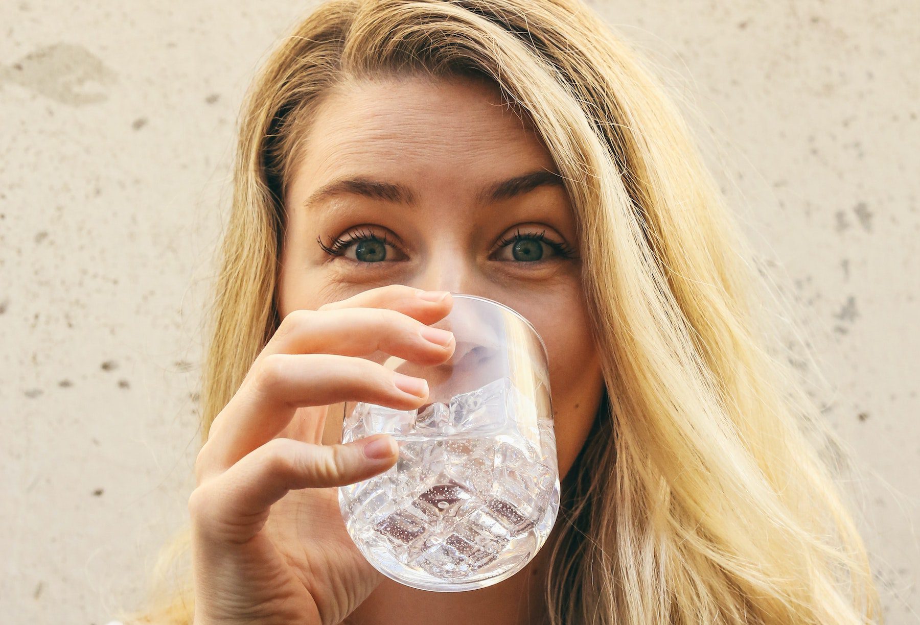 Happy blonde woman drinking water.