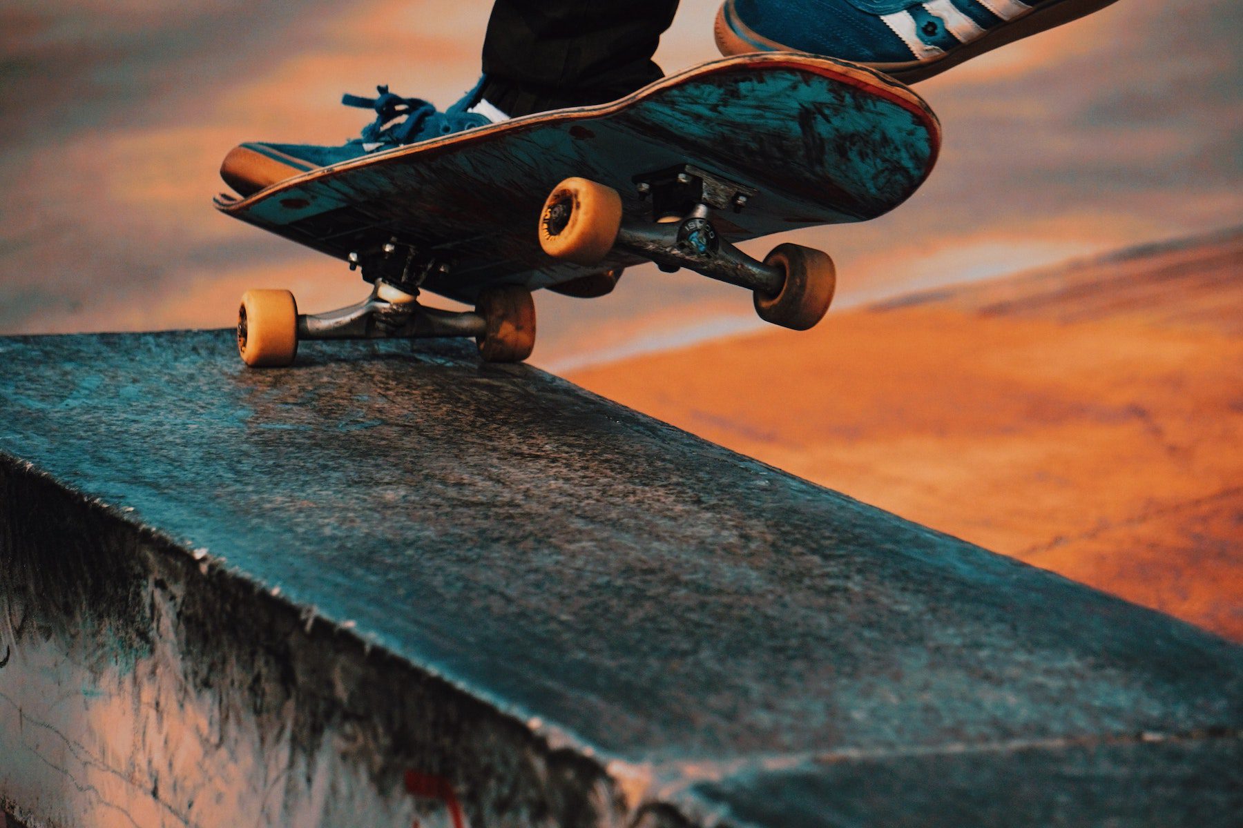 A closeup of a skateboarding performing a trick of grinding on a ledge